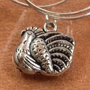 May include: Silver charm bracelet with a silver turkey charm. The turkey charm is detailed with a textured body and feathers.