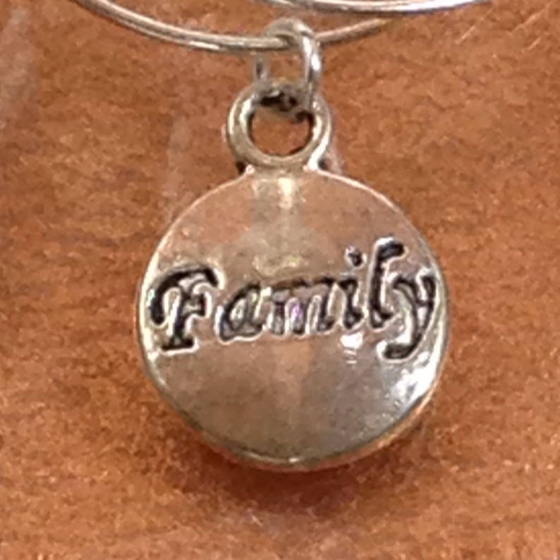 May include: Silver charm with the word "Family" engraved on it.