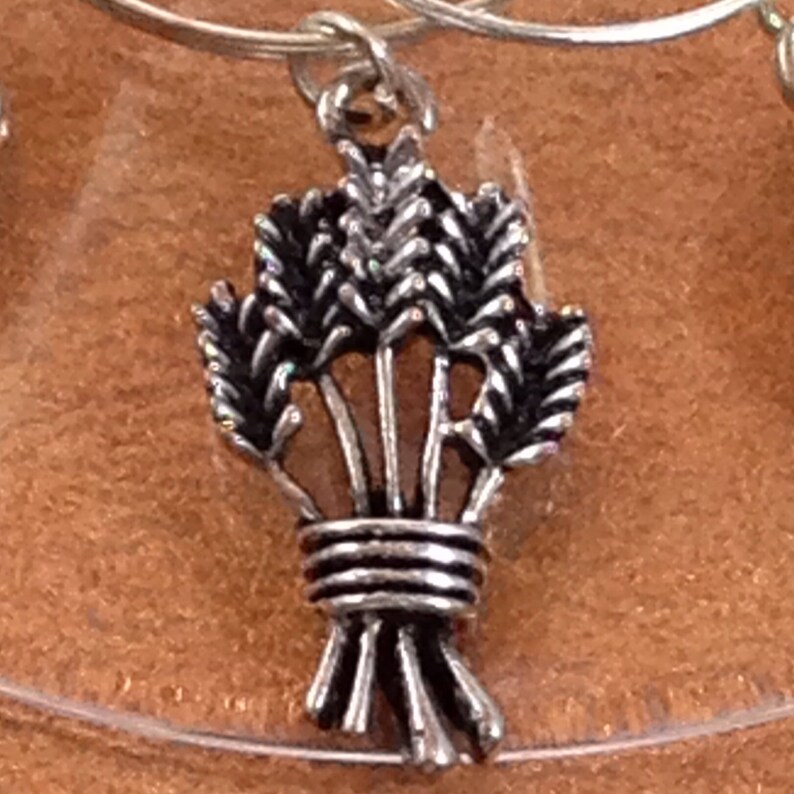 May include: Silver charm with a design of a bundle of wheat stalks tied together.