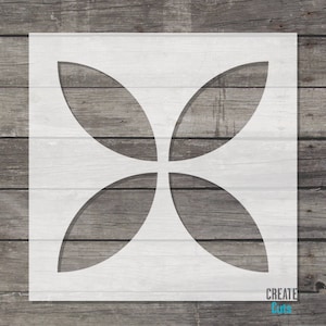 May include: White stencil with a geometric design of four overlapping circles, creating a four-leaf clover shape. The stencil is on a wood background.