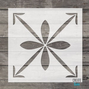 May include: White stencil with a geometric design featuring a flower with eight petals and four arrows pointing inwards. The stencil is on a wood background.