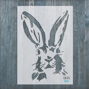 May include: White stencil of a rabbit's head with large ears. The stencil is on a blue wood background. The text "CREATE Cuts" is in the bottom right corner.