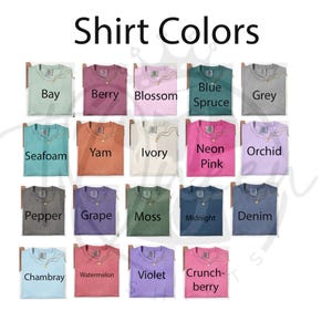 May include: A color chart titled Shirt Colors displaying nineteen t-shirts in various shades including Bay, Berry, Blossom, Blue Spruce, Grey, Seafoam, Yam, Ivory, Neon Pink, Orchid, Pepper, Grape, Moss, Midnight, Denim, Chambray, Watermelon, Violet, and Crunchberry.