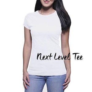Puede incluir: Una camiseta blanca con el texto "Next Level Tee" impreso en la parte delantera.