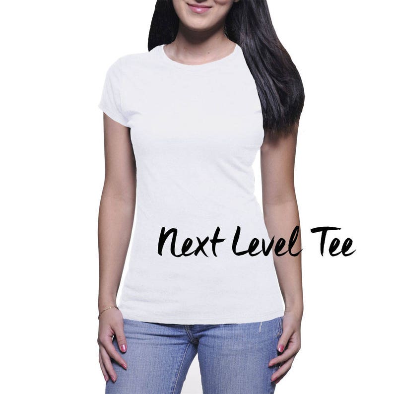 Puede incluir: Una camiseta blanca con el texto "Next Level Tee" impreso en la parte delantera.