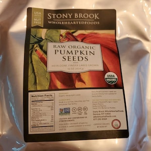 May include: A package of Stony Brook Raw Organic Pumpkin Seeds. The label indicates the seeds are heirloom, grown in the Finger Lakes region, and are USDA organic. The package contains 16 oz (454 g) of seeds and is nut-free.
