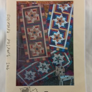 Könnte beinhalten: Ein beiges Papier mit dem Text "Everyday Runner" und "fat quarter friendly". Das Bild zeigt farbenfrohe, gesteppte Tischläufer mit floralen Mustern. In der unteren rechten Ecke steht der Text "G.E. DESIGNS ICELAND".