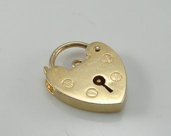 May include: A gold-colored heart-shaped padlock with a keyhole and a curved handle. The padlock has a keyhole and is secured with small screws. The overall design is simple and elegant, suitable for jewelry or decorative purposes.