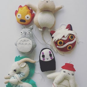 Op de afbeelding: Een set van zeven pluche knuffels met personages uit de Studio Ghibli-films. De knuffels zijn in verschillende kleuren, waaronder rood, wit, zwart, blauw en geel.