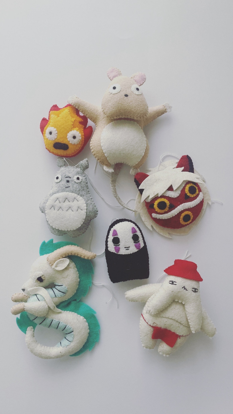 Op de afbeelding: Een set van zeven pluche knuffels met personages uit de Studio Ghibli-films. De knuffels zijn in verschillende kleuren, waaronder rood, wit, zwart, blauw en geel.