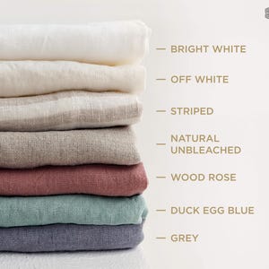 以下が含まれることがあります： Bright White、Off White、Striped、Natural Unbleached、Wood Rose、Duck Egg Blue、Greyとラベル付けされた様々な色の折り畳まれた布の山。画像の右上隅にThe Linen Valleyというテキストが表示されています。