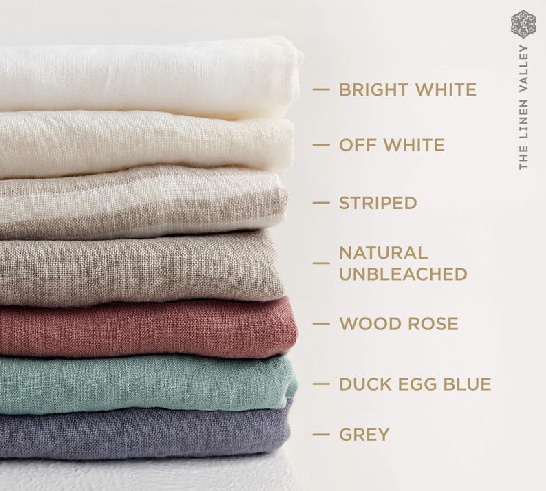 以下が含まれることがあります： Bright White、Off White、Striped、Natural Unbleached、Wood Rose、Duck Egg Blue、Greyとラベル付けされた様々な色の折り畳まれた布の山。画像の右上隅にThe Linen Valleyというテキストが表示されています。