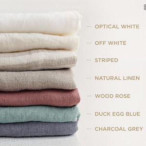 May include: A stack of eight linen fabric swatches in various colors, including optical white, off white, striped, natural linen, wood rose, duck egg blue, and charcoal grey. The swatches are arranged vertically with the names of each color listed to the right.