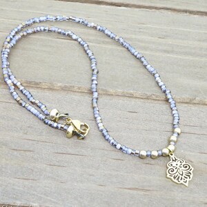 Purple beaded choker necklace with gold stainless steel flower pendant.