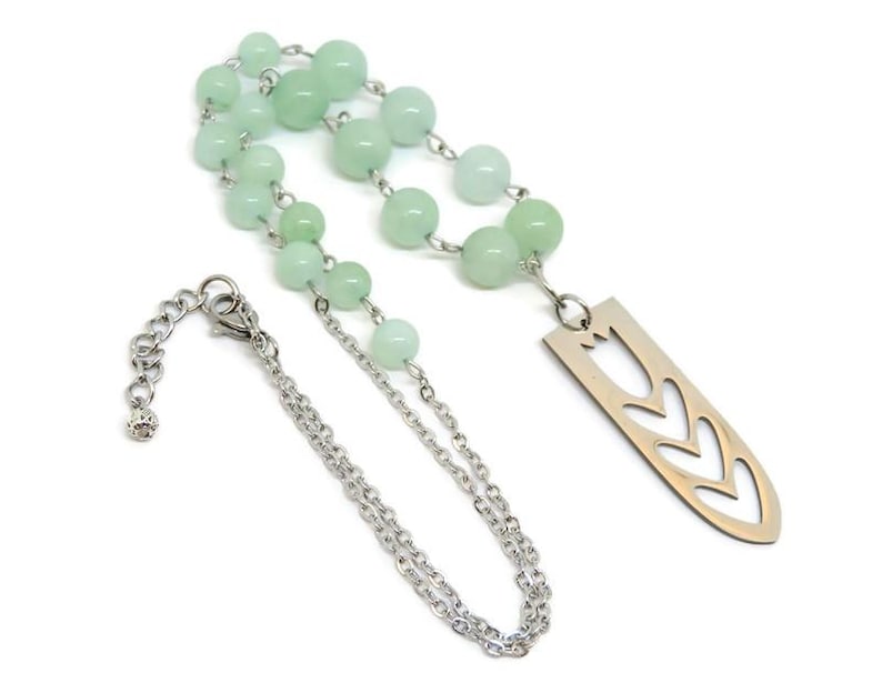 May include: A silver chain necklace with a silver pendant featuring a cut-out design of three tulips. The necklace is strung with light green beads.