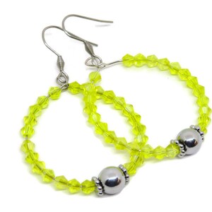 May include: A pair of hoop earrings with a silver bead accent. The hoops are made of clear yellow glass beads.