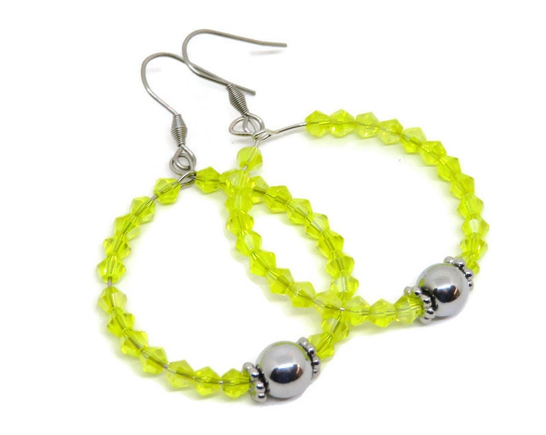 May include: A pair of hoop earrings with a silver bead accent. The hoops are made of clear yellow glass beads.