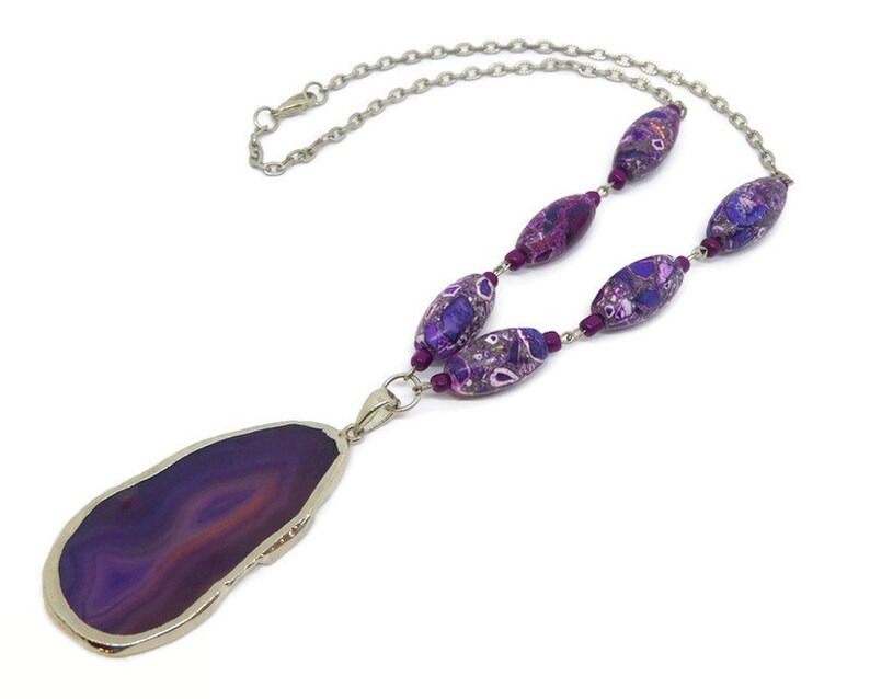May include: A purple agate pendant necklace with a silver chain and purple and silver beads.