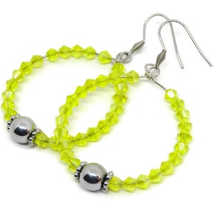 May include: A pair of hoop earrings with silver hooks and a silver bead accent. The hoops are made of clear yellow crystal beads.
