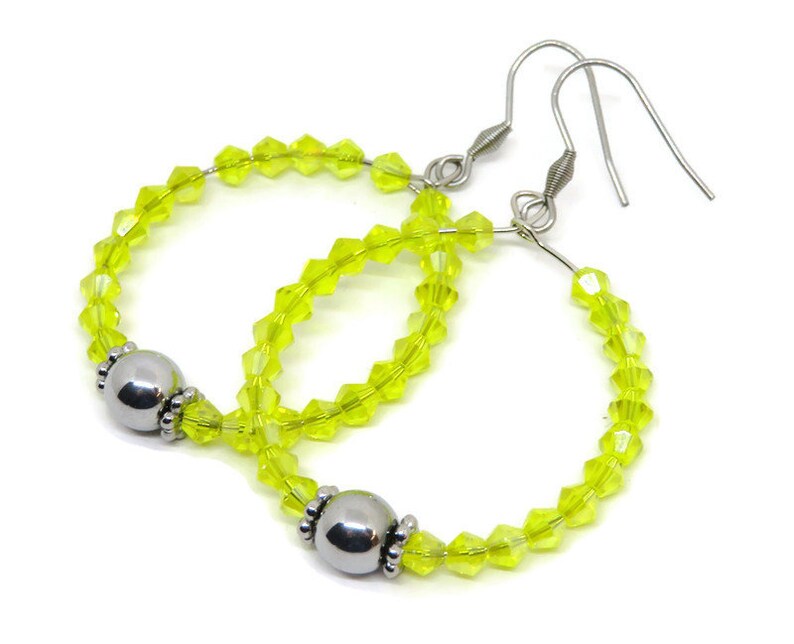 May include: A pair of hoop earrings with silver hooks and a silver bead accent. The hoops are made of clear yellow crystal beads.
