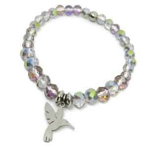 May include: A stretch bracelet composed of faceted, iridescent clear beads with a metallic finish. The bracelet features a silver-toned metal charm shaped like a hummingbird, suspended from a central silver-toned metal bead spacer.