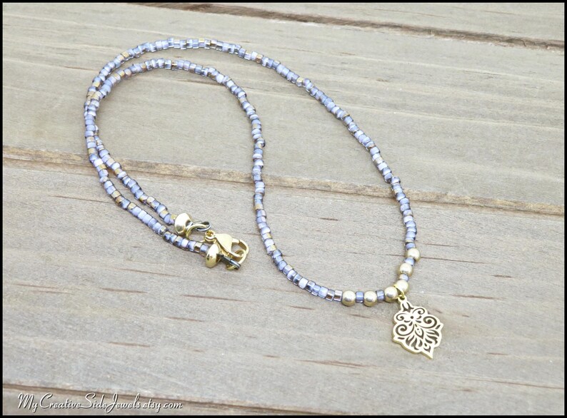 Purple beaded choker necklace with gold stainless steel flower pendant.
