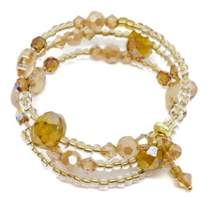 Puede incluir: Una pulsera envolvente de m&uacute;ltiples hilos con cuentas &aacute;mbar y transparentes. La pulsera tiene un alambre de metal dorado y un dije decorativo con cuentas colgantes. Las cuentas var&iacute;an en tama&ntilde;o y forma, creando un dise&ntilde;o texturizado y llamativo.