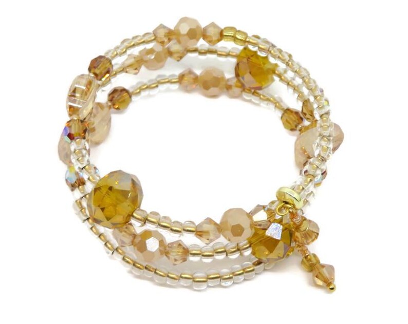 Puede incluir: Una pulsera envolvente de m&uacute;ltiples hilos con cuentas &aacute;mbar y transparentes. La pulsera tiene un alambre de metal dorado y un dije decorativo con cuentas colgantes. Las cuentas var&iacute;an en tama&ntilde;o y forma, creando un dise&ntilde;o texturizado y llamativo.