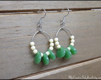 May include: A pair of silver hoop earrings with green and white beads. The earrings have a simple design and are perfect for everyday wear.