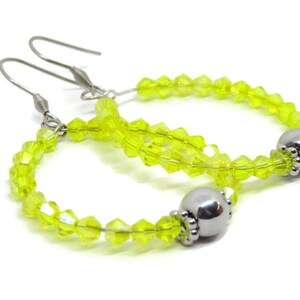May include: A pair of lime green crystal bead hoop earrings with silver metal hooks and a silver bead accent.