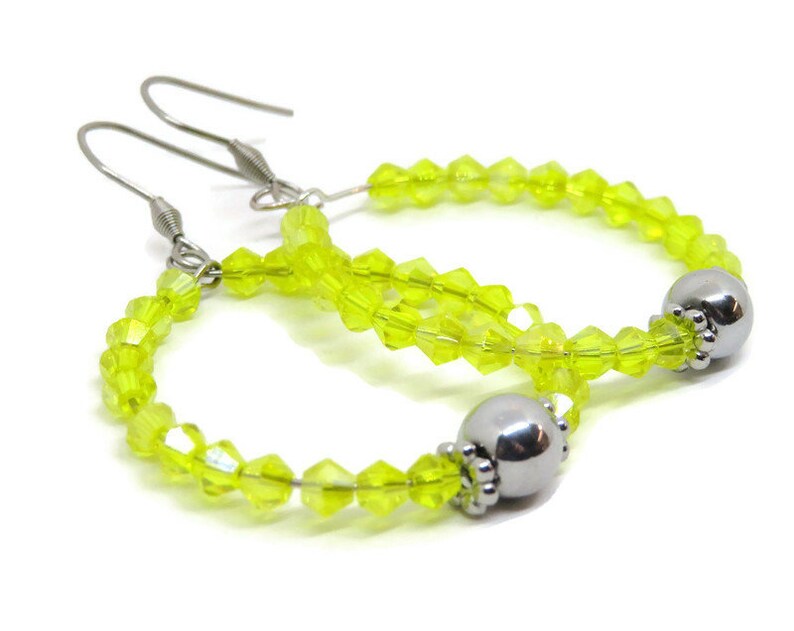 May include: A pair of lime green crystal bead hoop earrings with silver metal hooks and a silver bead accent.