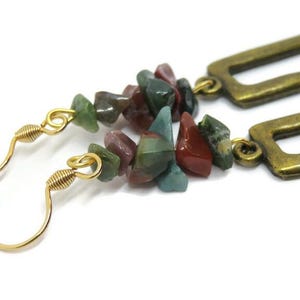 May include: Gold dangle earrings with a rectangular frame and a cluster of green, red, and brown gemstone chips.