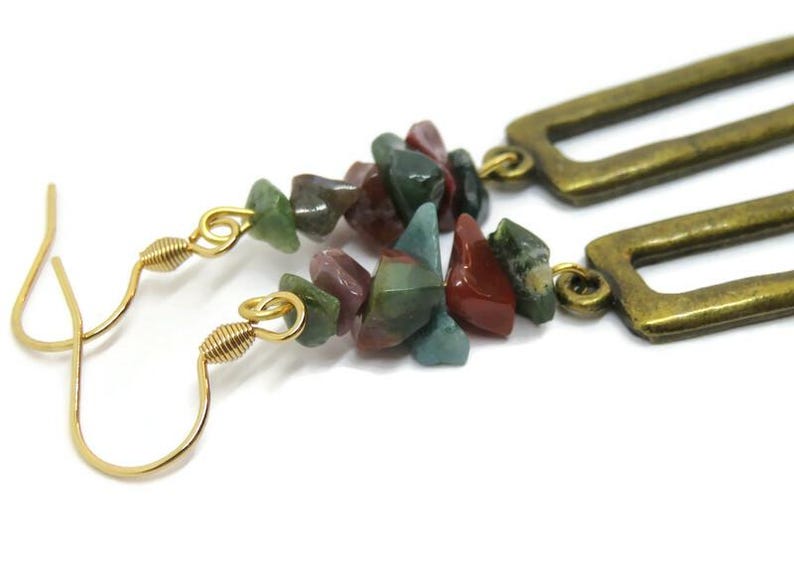 May include: Gold dangle earrings with a rectangular frame and a cluster of green, red, and brown gemstone chips.