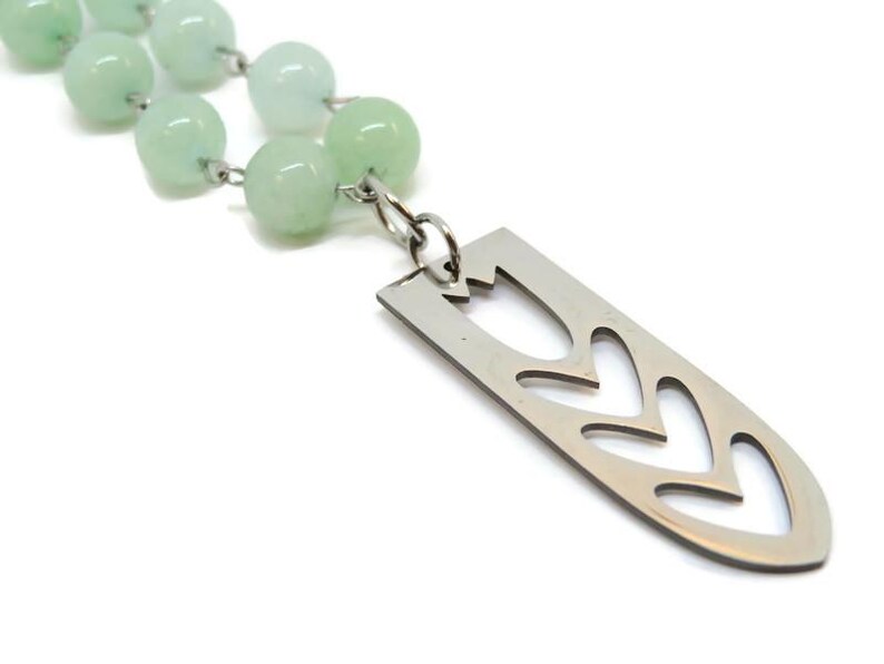 May include: A green jade bead necklace with a silver pendant featuring a cut-out tulip design.