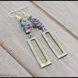 May include: A pair of long, gold-toned earrings with a rectangular pendant. The earrings are adorned with a cascade of colourful, irregularly shaped stones.