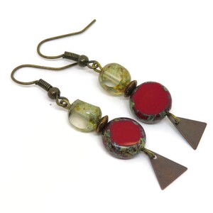 Op de afbeelding: Een paar oorhangers met een rood, groen en gouden kleurenschema. De oorhangers hebben een rode en groene gespikkelde ronde kraal, een heldere glazen kraal met gouden vlekken en een kleine driehoekige hanger.