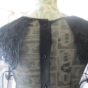 May include: A black sheer blouse with a large black lace collar. The blouse has a button-up back.