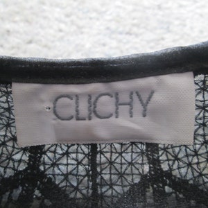 May include: A white tag with black embroidered text that reads "CLICHY" on a black mesh fabric.