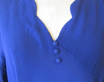 May include: A royal blue blouse with a scalloped neckline and three buttons down the front.
