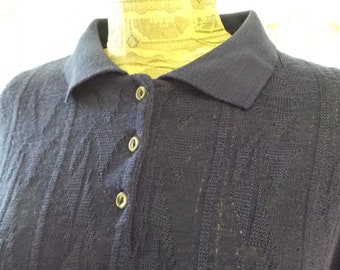 May include: A navy blue knitted polo shirt with a button-up closure. The shirt has a cable knit pattern and a classic collar.