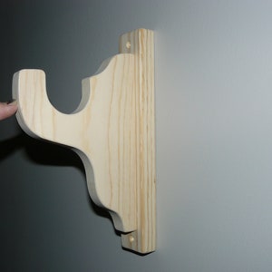 May include: A wooden shelf bracket with a decorative design. The bracket is made of unfinished pine wood and is ready to be stained or painted.