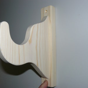 May include: A wooden shelf bracket with a decorative scroll design. The bracket is unfinished and ready to be painted or stained.