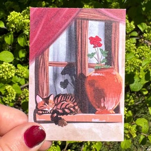 May include: A watercolor painting of a window scene. A sleeping tabby cat rests on the windowsill. A red curtain hangs to the left. A terracotta vase holds a red flower. The window reveals a silhouette of plants.