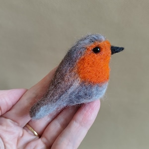 Peut inclure: Figurine d'oiseau rouge-gorge en feutre fait à la main. L'oiseau présente une poitrine orange vif, des ailes et un dos gris, et un petit bec noir. Un charmant objet de décoration.