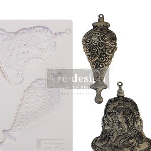 May include: An image featuring a white silicone mold with ornate, vintage-style designs, alongside two decorative metal ornaments. The ornaments have intricate patterns and a distressed finish, suggesting an antique aesthetic. The text "re-design with prima" is visible.