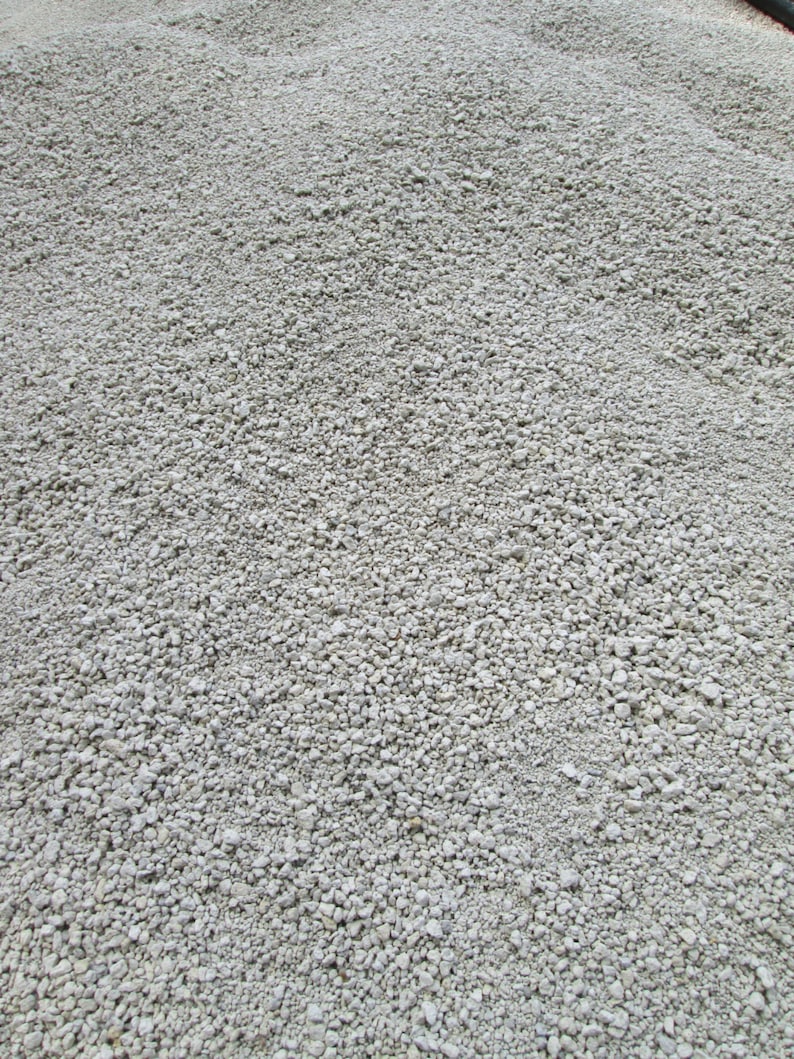 May include: A close-up view of a pile of small, white, round gravel. The gravel is evenly distributed and appears to be dry.