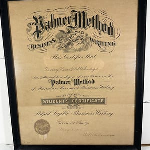 May include: Framed certificate from The Palmer Method of Business Writing. The certificate, in a black frame, features ornate script and a detailed illustration. The text includes the name "Henry Van Oddlehings" and the date "May 9, 1921".