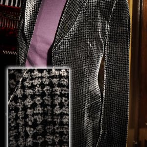 Könnte beinhalten: Ein schwarzer und weißer Hahnentritt-Blazer mit einem einzigen Knopfverschluss. Der Blazer ist aus einem weichen, samtigen Stoff gefertigt.