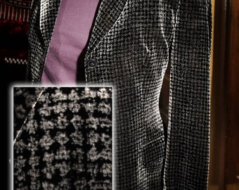 May include: A black and white houndstooth patterned blazer with a single button closure. The blazer is made of a soft, velvety fabric.