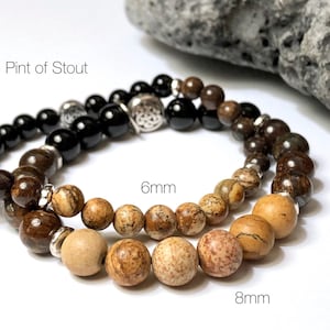 May include: Two bracelets with brown and black beads. The smaller bracelet has 6mm beads and the larger bracelet has 8mm beads. The larger bracelet has a silver charm with a Celtic knot design. The text "Pint of Stout" is visible in the image.